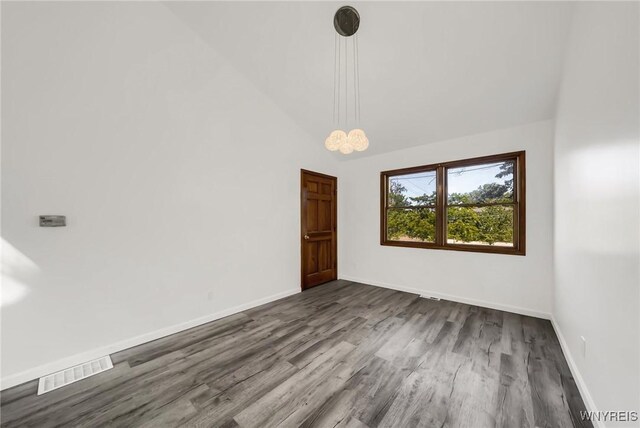 unfurnished room featuring high vaulted ceiling, wood-type flooring, and a chandelier