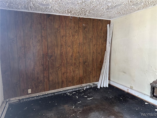 unfurnished room with a textured ceiling and wooden walls