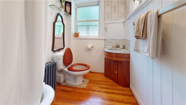 bathroom featuring wood-type flooring, toilet, radiator heating unit, and vanity