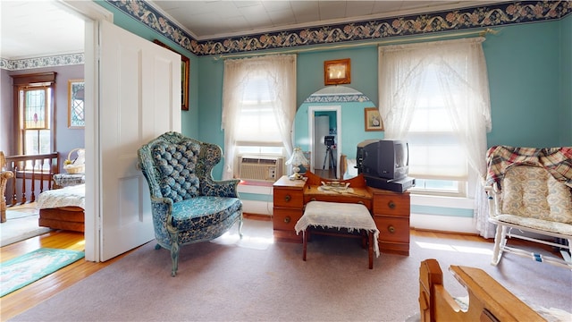 sitting room with hardwood / wood-style flooring, ornamental molding, and a healthy amount of sunlight