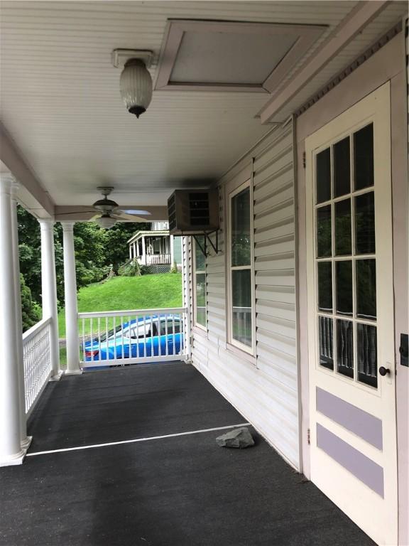 view of patio / terrace featuring ceiling fan, covered porch, and a wall mounted air conditioner