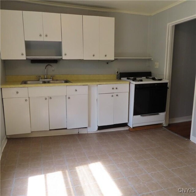 kitchen featuring crown molding, white stove, light tile patterned floors, sink, and white cabinets