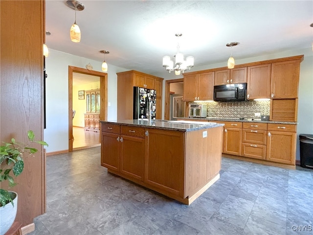 kitchen featuring tasteful backsplash, an island with sink, decorative light fixtures, and stainless steel refrigerator