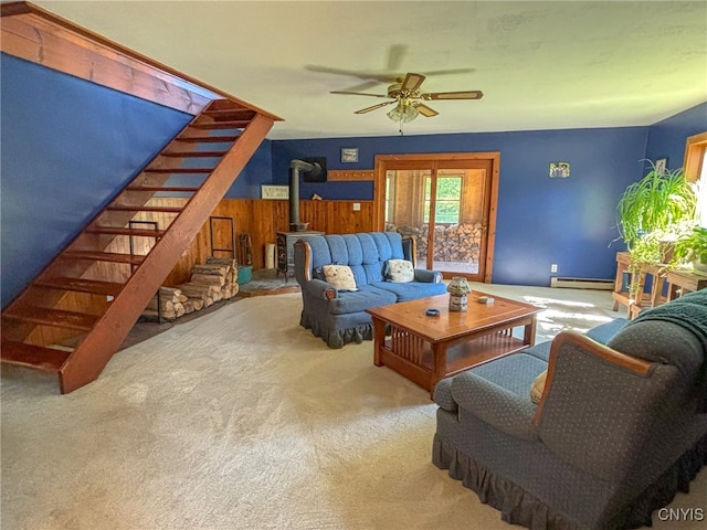 carpeted living room with a baseboard heating unit, ceiling fan, and a wood stove