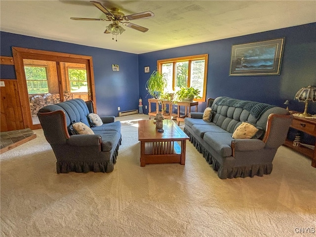 living room with a baseboard heating unit, ceiling fan, plenty of natural light, and carpet