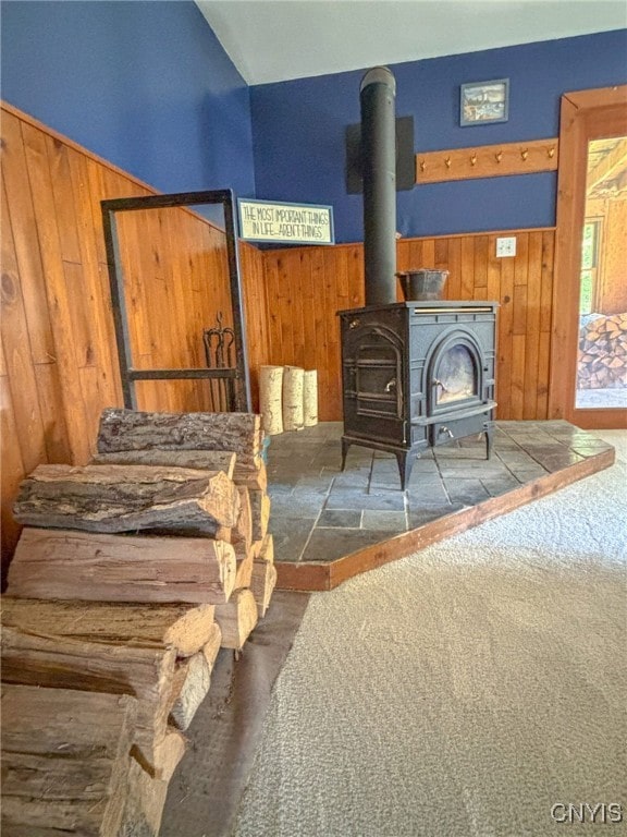 interior space featuring lofted ceiling, wood walls, and a wood stove