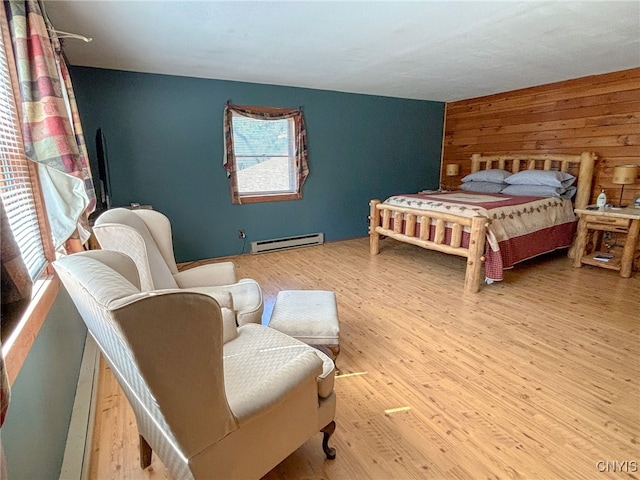 bedroom featuring wood walls, a baseboard radiator, and light hardwood / wood-style floors