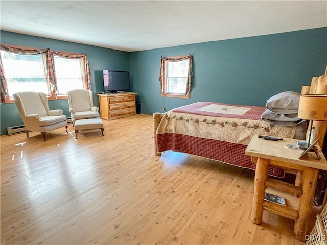 bedroom featuring a baseboard heating unit and light hardwood / wood-style flooring