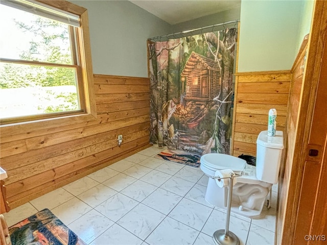 bathroom with wood walls, a shower with curtain, and toilet