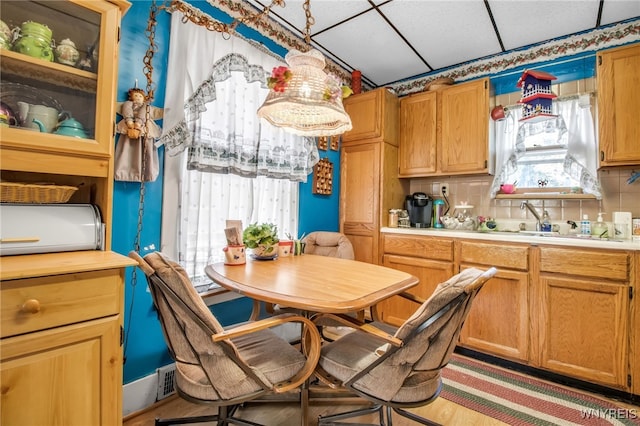 kitchen featuring a paneled ceiling, sink, light hardwood / wood-style flooring, and backsplash