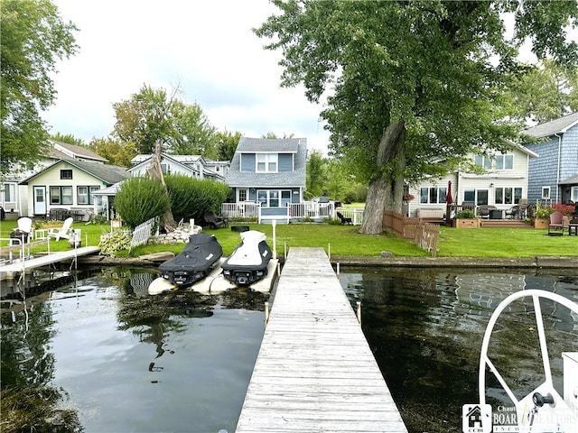 view of dock featuring a lawn and a water view