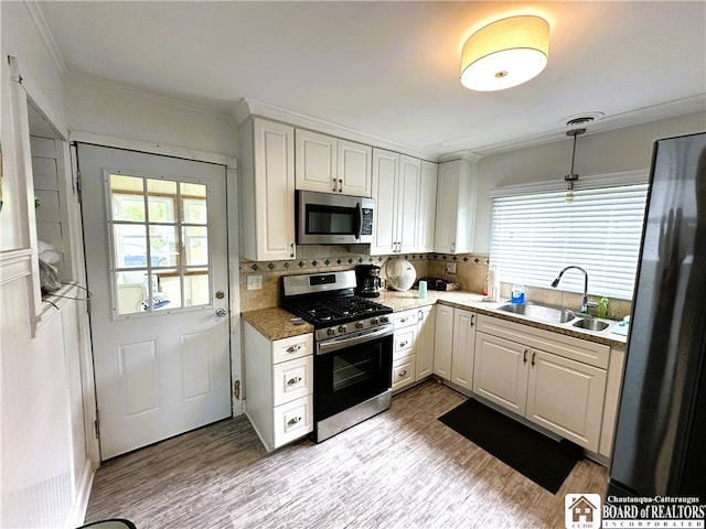 kitchen featuring white cabinetry, tasteful backsplash, stainless steel appliances, sink, and light hardwood / wood-style floors