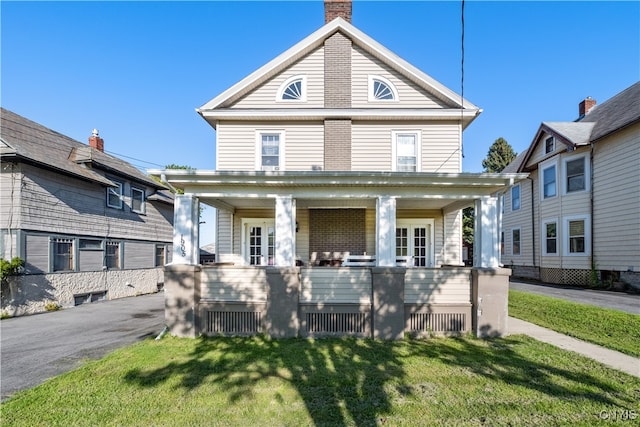 view of front of home featuring a garage, a porch, and a front lawn