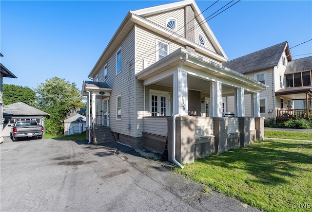 view of home's exterior featuring a garage, a porch, an outbuilding, and a lawn