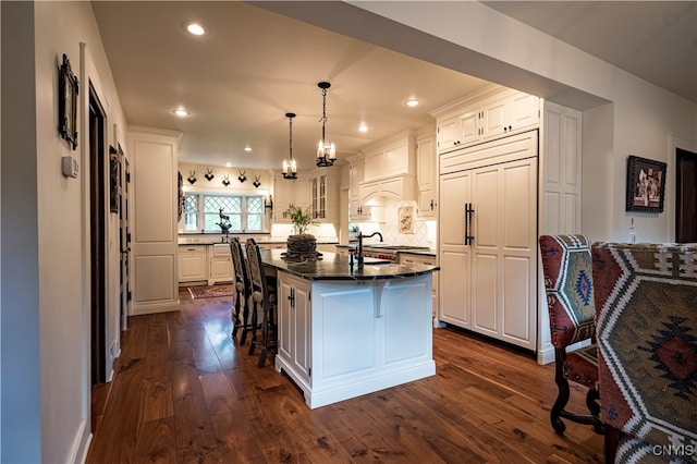 kitchen with paneled built in fridge, white cabinetry, a kitchen breakfast bar, a kitchen island, and dark wood-type flooring