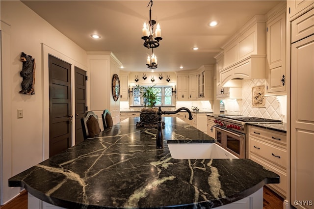 kitchen featuring a notable chandelier, a spacious island, high end stainless steel range, and dark stone counters