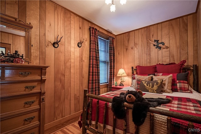 bedroom featuring crown molding, wooden walls, and light hardwood / wood-style floors