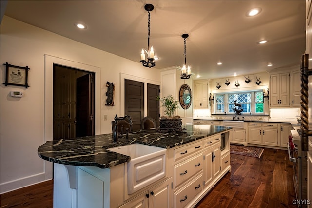 kitchen featuring dark hardwood / wood-style floors, a center island, sink, white cabinetry, and dark stone countertops