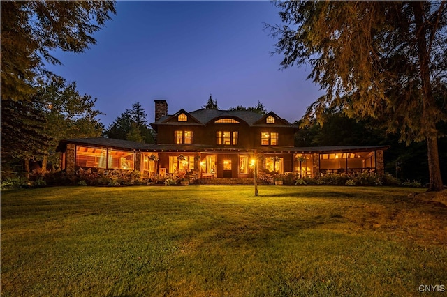 back house at dusk featuring a yard