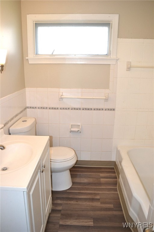 bathroom featuring vanity, wood-type flooring, a bathing tub, and a wealth of natural light