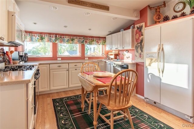 kitchen with white appliances, lofted ceiling with beams, light hardwood / wood-style flooring, and white cabinets