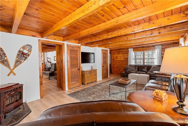 living room featuring beamed ceiling, wooden walls, wooden ceiling, and light hardwood / wood-style floors