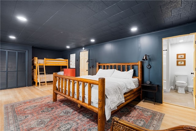 bedroom featuring light wood-type flooring, ensuite bathroom, and a closet