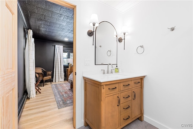 bathroom with a baseboard radiator, hardwood / wood-style flooring, and vanity