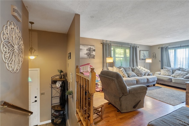 living room with hardwood / wood-style floors, a textured ceiling, and a healthy amount of sunlight