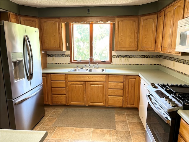 kitchen with a textured ceiling, sink, white appliances, and decorative backsplash