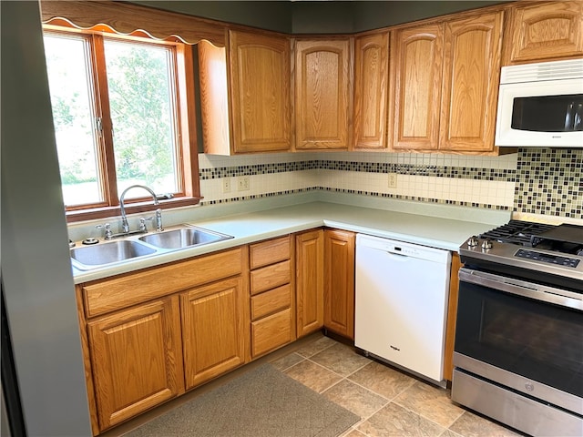 kitchen featuring white appliances, plenty of natural light, sink, and decorative backsplash