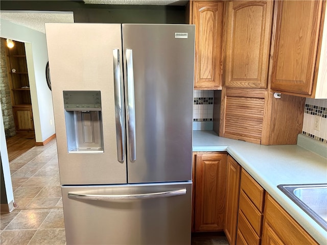 kitchen featuring a textured ceiling, sink, tasteful backsplash, and stainless steel refrigerator with ice dispenser