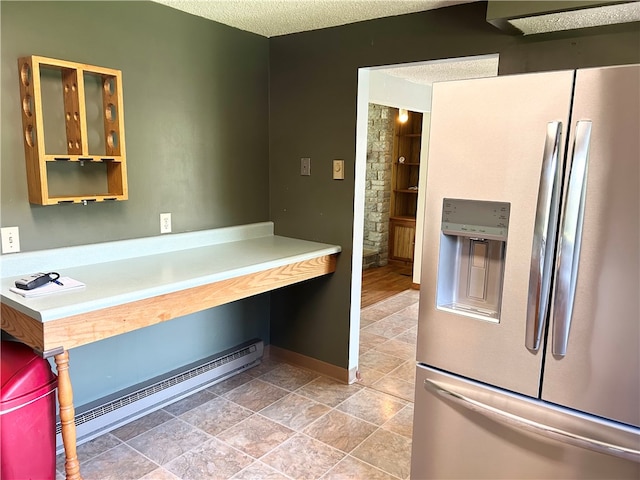 interior space featuring stainless steel fridge, a baseboard radiator, and a textured ceiling