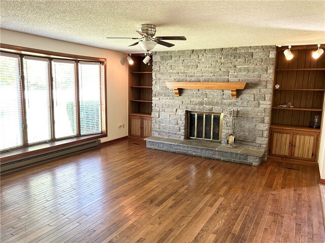 unfurnished living room with a textured ceiling, hardwood / wood-style floors, a stone fireplace, ceiling fan, and baseboard heating