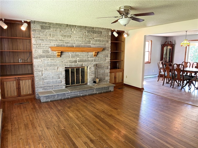 unfurnished living room with dark hardwood / wood-style flooring, a baseboard radiator, a stone fireplace, ceiling fan, and a textured ceiling