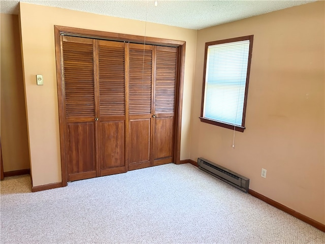 unfurnished bedroom featuring a baseboard heating unit, light colored carpet, a closet, and a textured ceiling