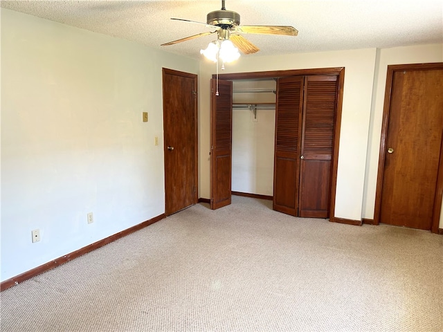 unfurnished bedroom featuring a textured ceiling, light colored carpet, and ceiling fan