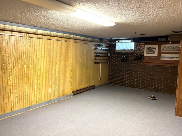 basement featuring a baseboard heating unit, a textured ceiling, and wood walls