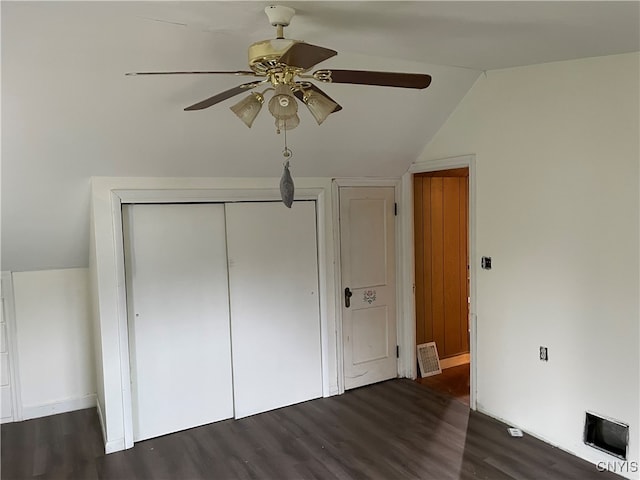 unfurnished bedroom featuring lofted ceiling, dark wood-type flooring, ceiling fan, and a closet