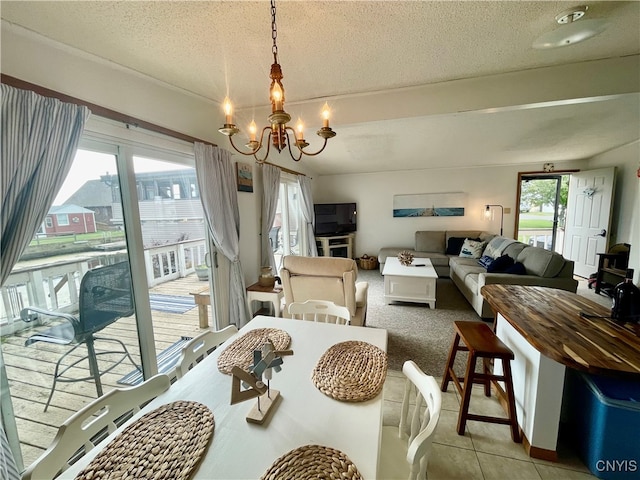 dining space with a textured ceiling, light tile patterned floors, and a chandelier