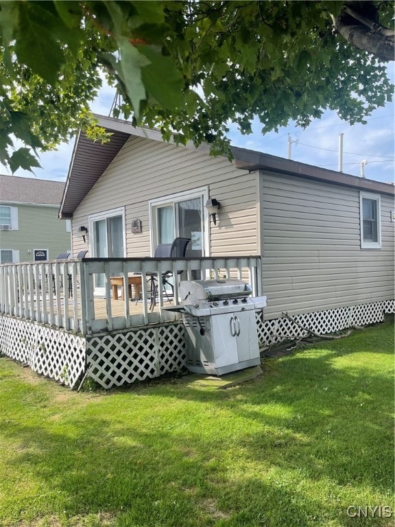 rear view of house featuring a wooden deck and a yard