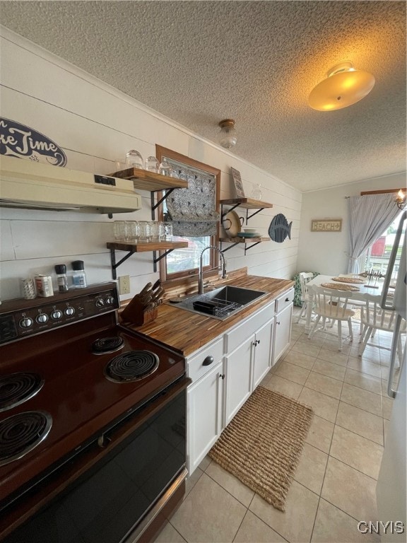 kitchen featuring a textured ceiling, black range with electric cooktop, sink, and wooden counters