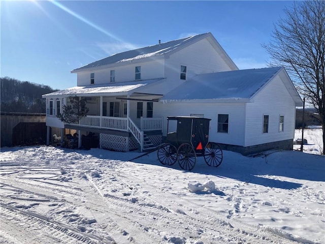 snow covered back of property featuring a porch