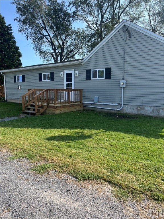 rear view of house with a wooden deck and a lawn