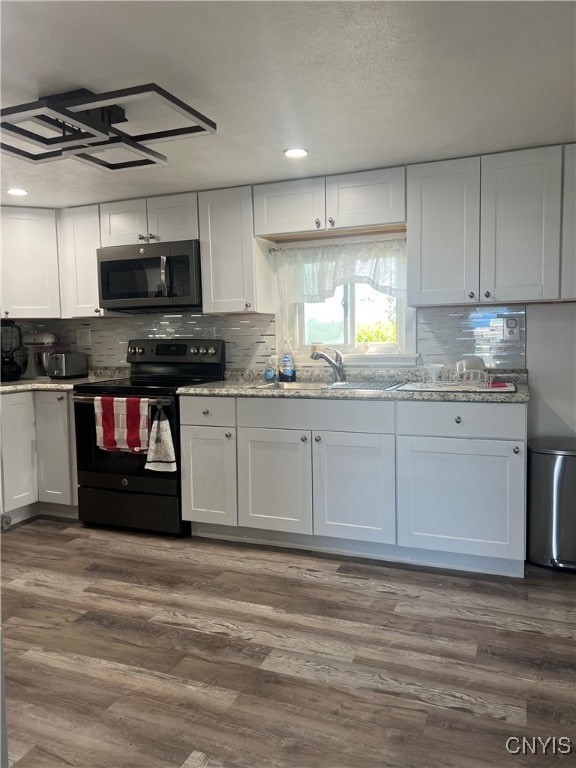 kitchen with black electric range oven, sink, hardwood / wood-style floors, and white cabinets