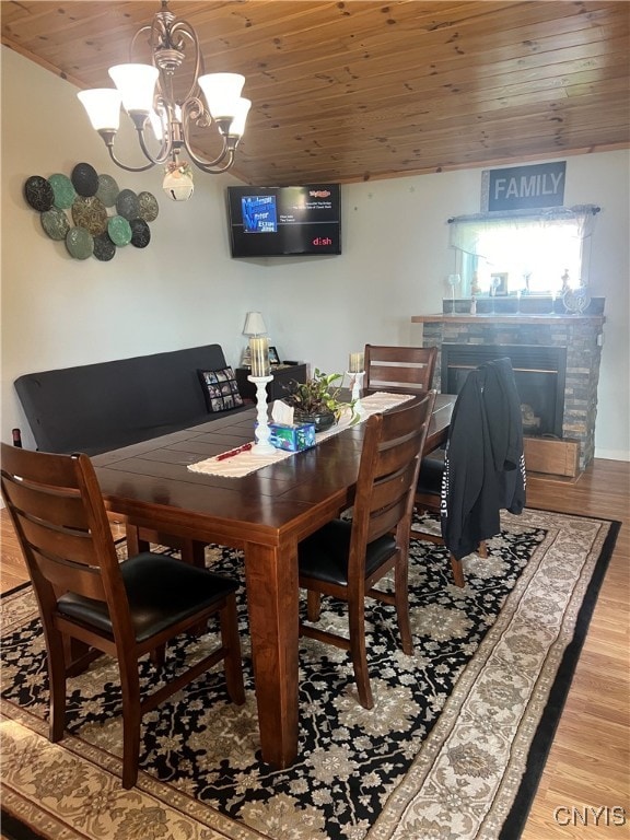 dining space with light hardwood / wood-style flooring, an inviting chandelier, and wooden ceiling