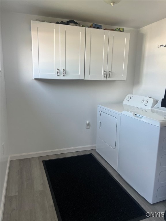 laundry room featuring hardwood / wood-style flooring, cabinets, and washing machine and dryer