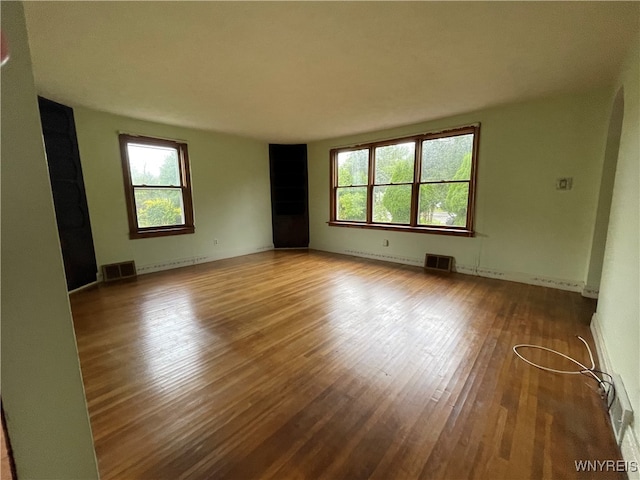 spare room featuring hardwood / wood-style flooring, a healthy amount of sunlight, and baseboard heating