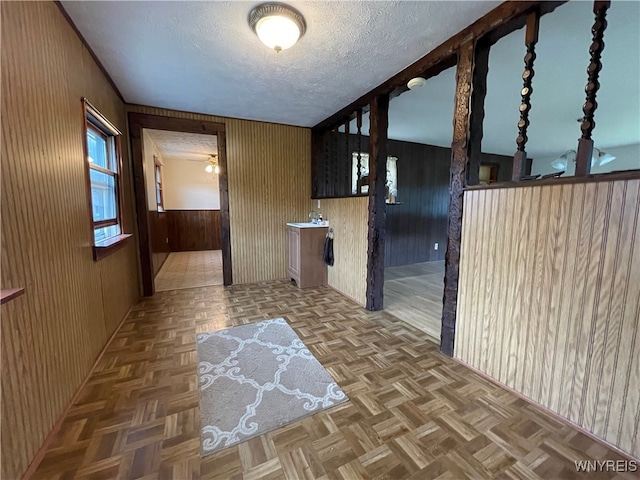 corridor with parquet flooring, wooden walls, and a textured ceiling