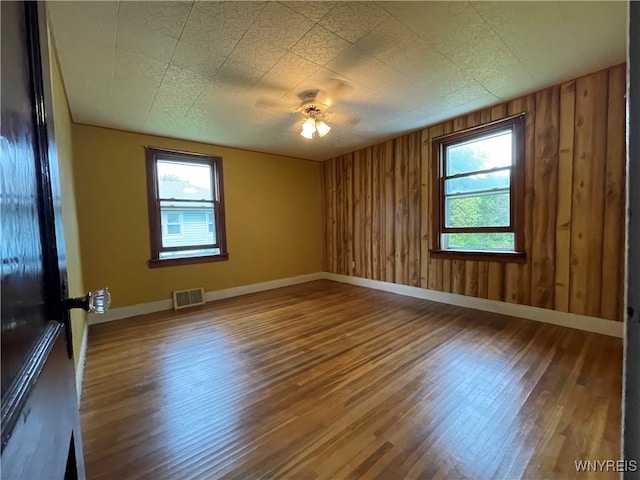 spare room featuring wood walls, plenty of natural light, and hardwood / wood-style floors